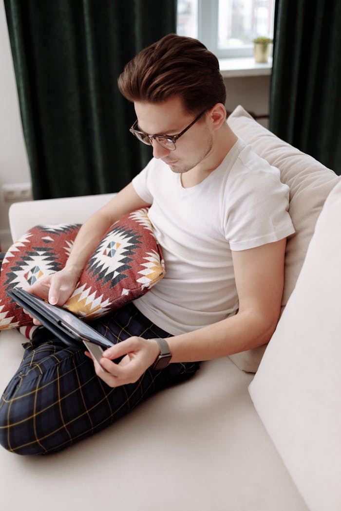 Man in glasses shopping online using tablet and credit card at home.
