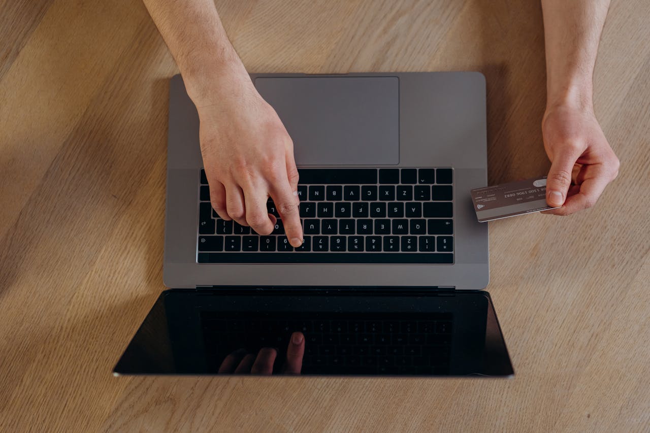 Services Top view of hands using a credit card and laptop for online transactions on a wooden surface.